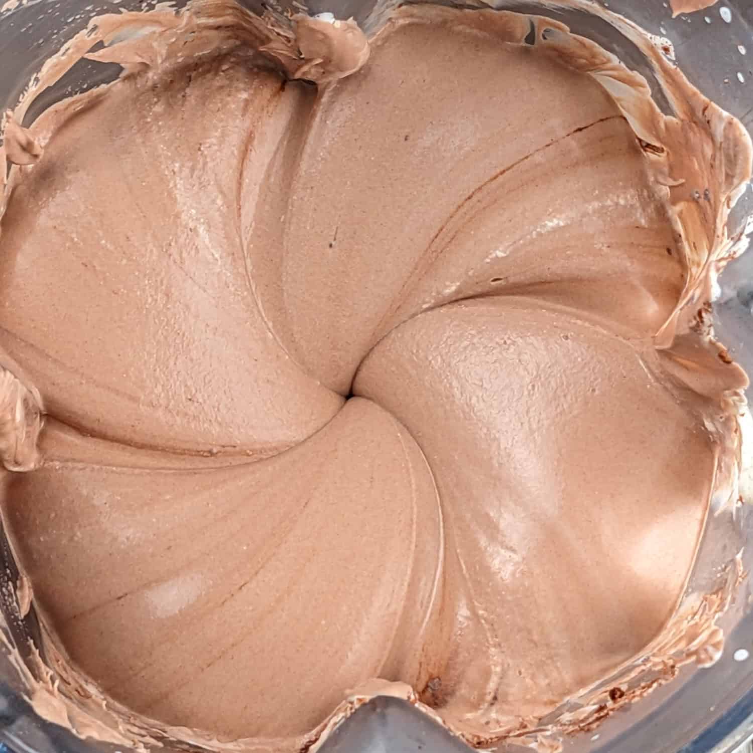 Creamy chocolate mixture swirls in a blender, perfect for no-churn ice cream recipes.